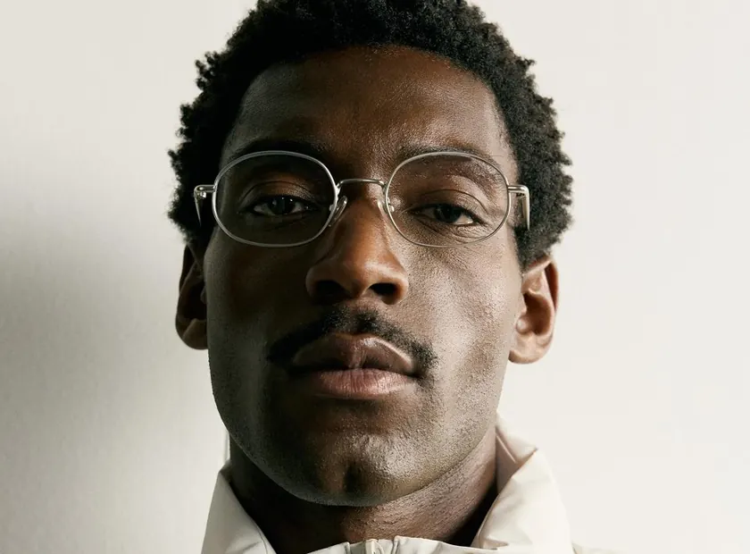 A young man in glasses and a cream puffer jacket