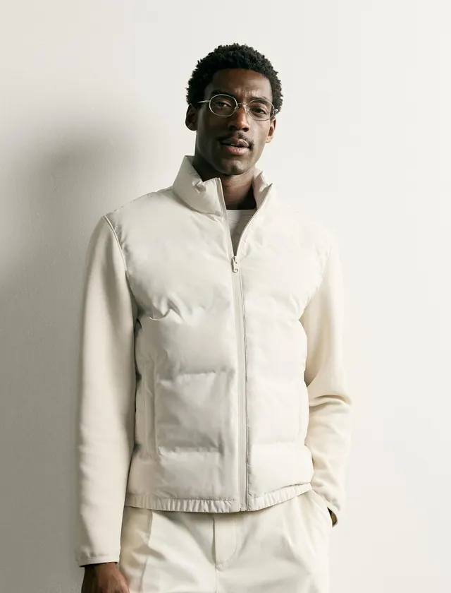 A man in a cream puffer jacket and cream trousers
